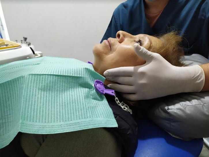 imagen de un dentista palpando el cuello de un paciente